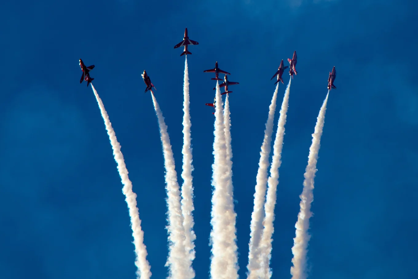 Seven jets emitting white smoke trails in sky.