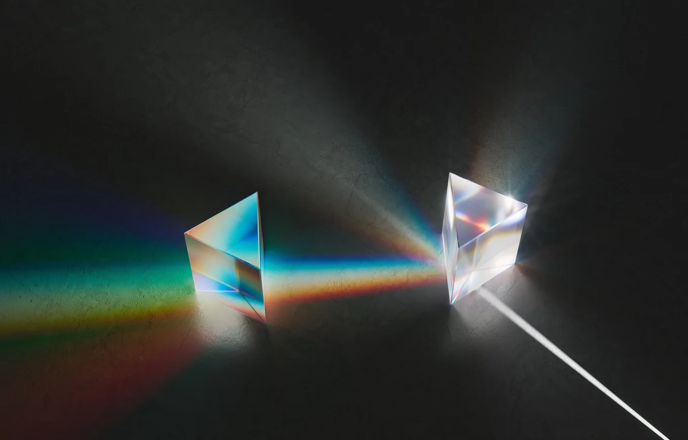 Two glass prisms with rainbow light dispersion.